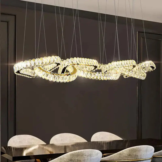 A gold-toned decorbites crystal chandelier with an intertwined design and clear crystals for living and dining rooms