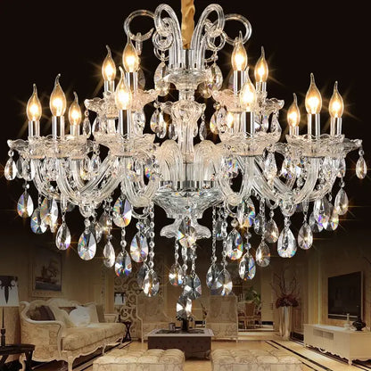 A decorbites crystal chandelier with multiple tiers of teardrop crystals and silver arms illuminated by warm bulbs