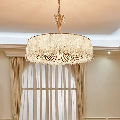 A luxurious gold-toned decorbites crystal chandelier with cascading crystal fringe for villa hall and bedroom lighting