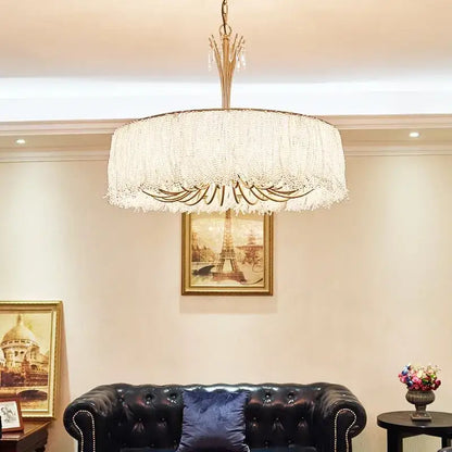 A luxurious gold-toned decorbites crystal chandelier with cascading crystal fringe for villa hall and bedroom lighting