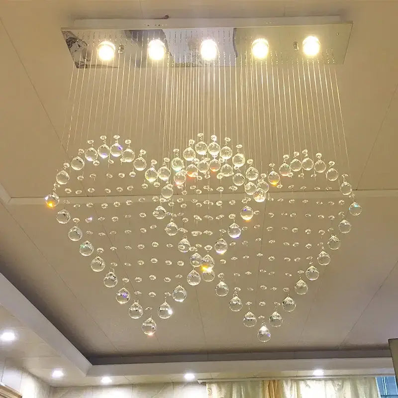 A heart-shaped decorbites crystal chandelier with clear glass beads and a sleek metallic fixture for dining rooms