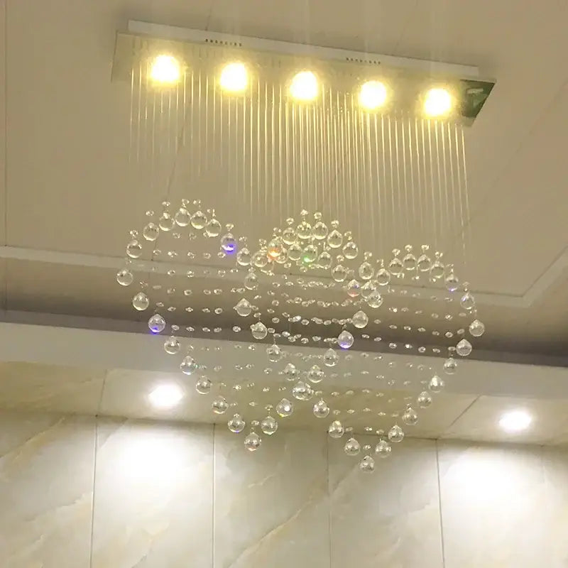 A decorbites crystal chandelier with a modern heart-shaped design featuring clear glass beads for bedroom and dining lighting