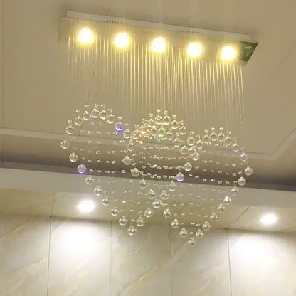 A decorbites crystal chandelier with a modern heart-shaped design featuring clear glass beads for bedroom and dining lighting