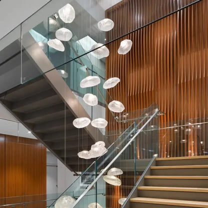 A modern translucent white glass decorbites crystal chandelier with cloud design hangs above staircase lighting interior