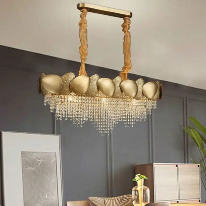 Gold-toned decorbites crystal chandelier with sculptural shell-like fixtures and cascading crystal droplets for living room