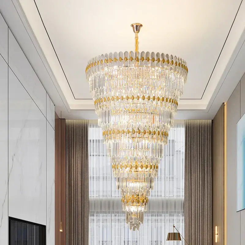 A multi-tiered decorbites crystal chandelier with gold accents and cascading clear glass prisms for luxury lighting