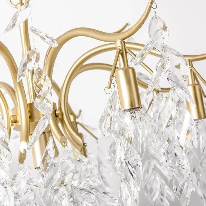 A decorbites crystal chandelier with delicate gold-toned frame and cascading clear crystal leaves for modern luxury lighting