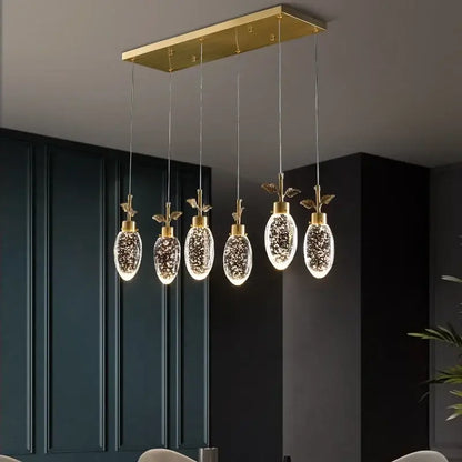Gold-toned decorbites crystal chandelier with five oval glass pendants featuring sparkling glitter and gold leaf accents