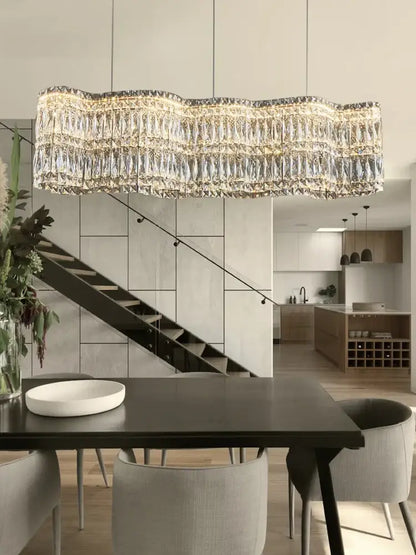 A modern DecorBites crystal chandelier pendant light with wavy gold metal frame and cascading crystal prisms