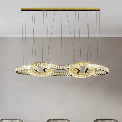 Gold-toned decorbites crystal chandelier pendant light with flowing ring design suspended by black cords for living room