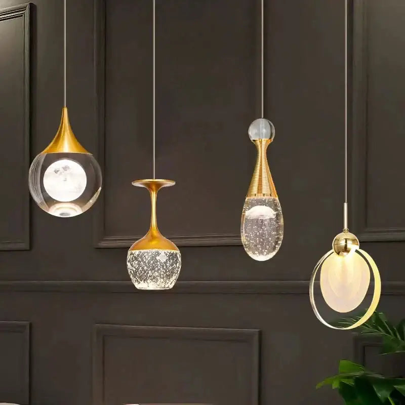 Four elegant gold-toned decorbites crystal led pendant lights with unique vase-like glass shades for dining room use