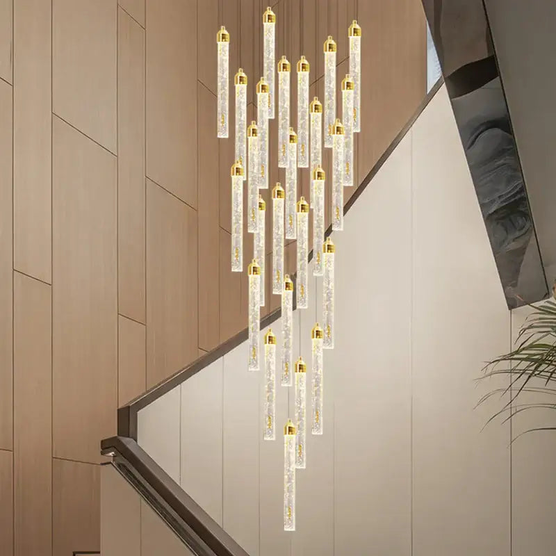 A decorbites crystal staircase chandelier led with modern vertical glass tubes, gold caps, and internal LED lighting