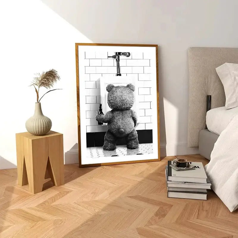 A framed black-and-white canvas print featuring a cute bear bathroom scene with a gray teddy bear and white tiles