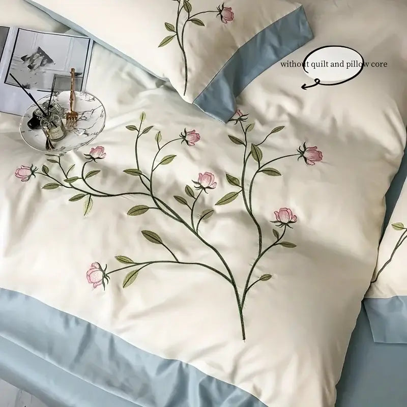 Cream-colored satin duvet cover set with elegant embroidery featuring pink rose and soft blue piping by DecorBites