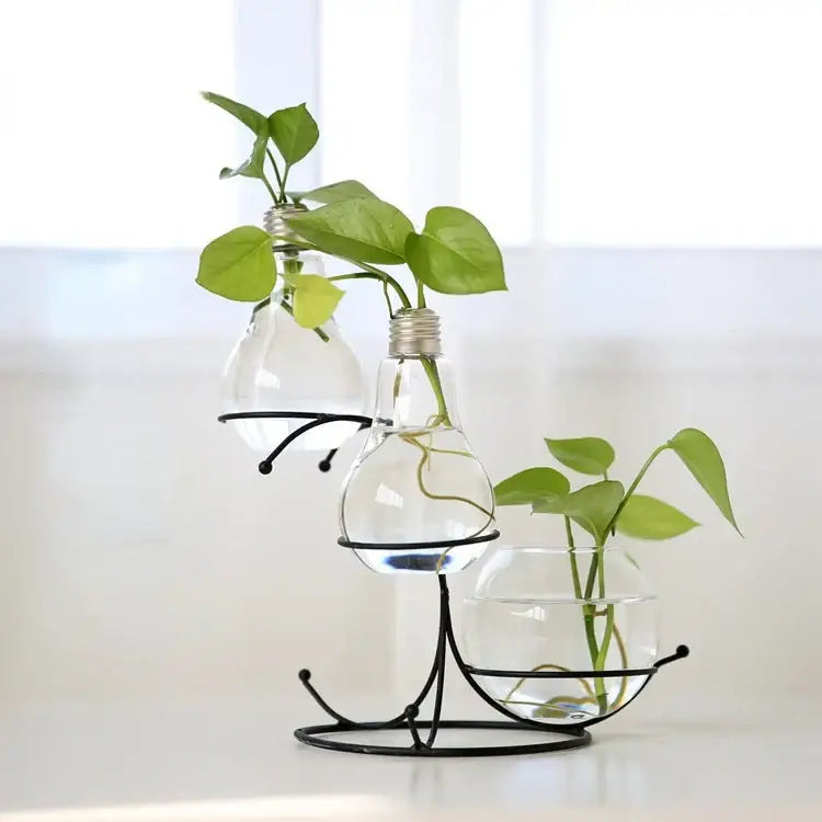 DecorBites™ flamingo metal vase with clear glass bulb vases and green plants on a black metal stand for home decor