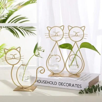 Gold wireframe cat-shaped metal vase with clear glass interior holding small plants for DecorBites home decor