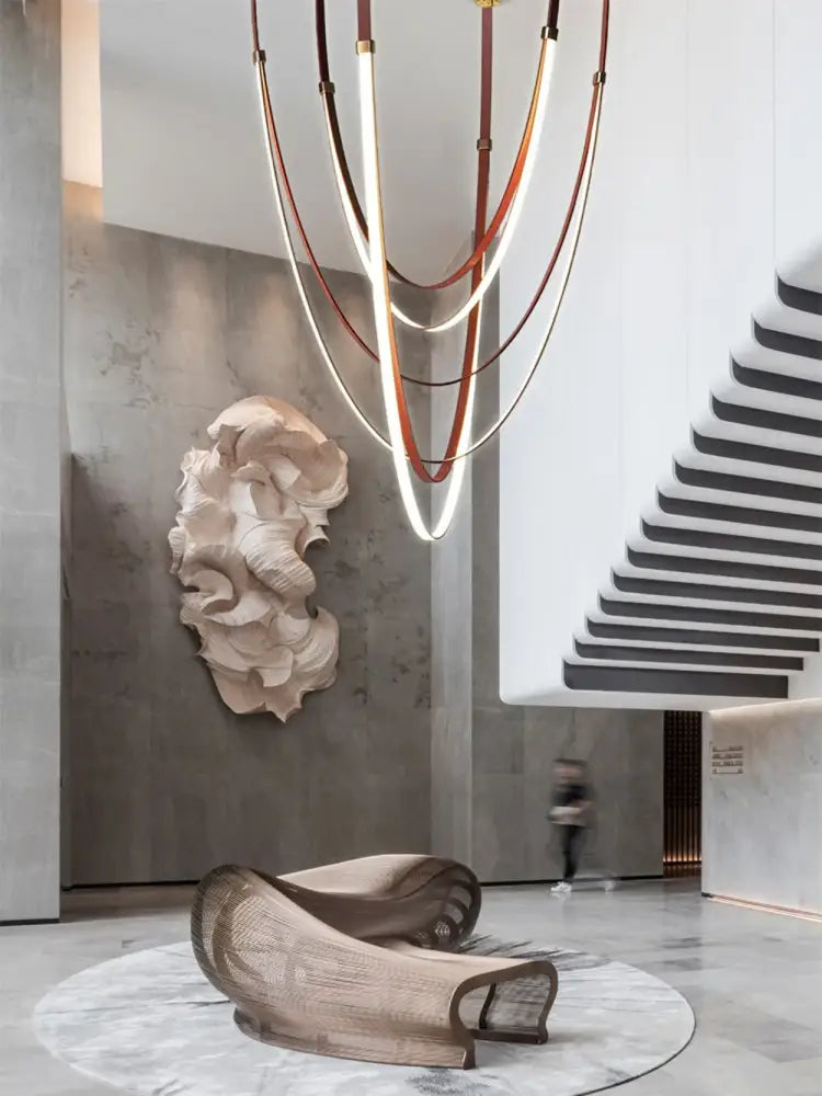 A sculptural beige-toned lounge chair with woven mesh and curved metal frame paired with a decorbites led chandelier light