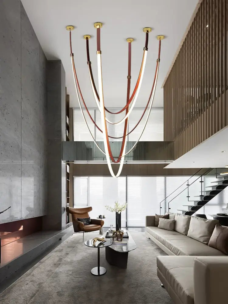 DecorBites™ flexible leather belt LED chandelier with curved illuminated tubes suspended by brown leather straps and gold fixtures