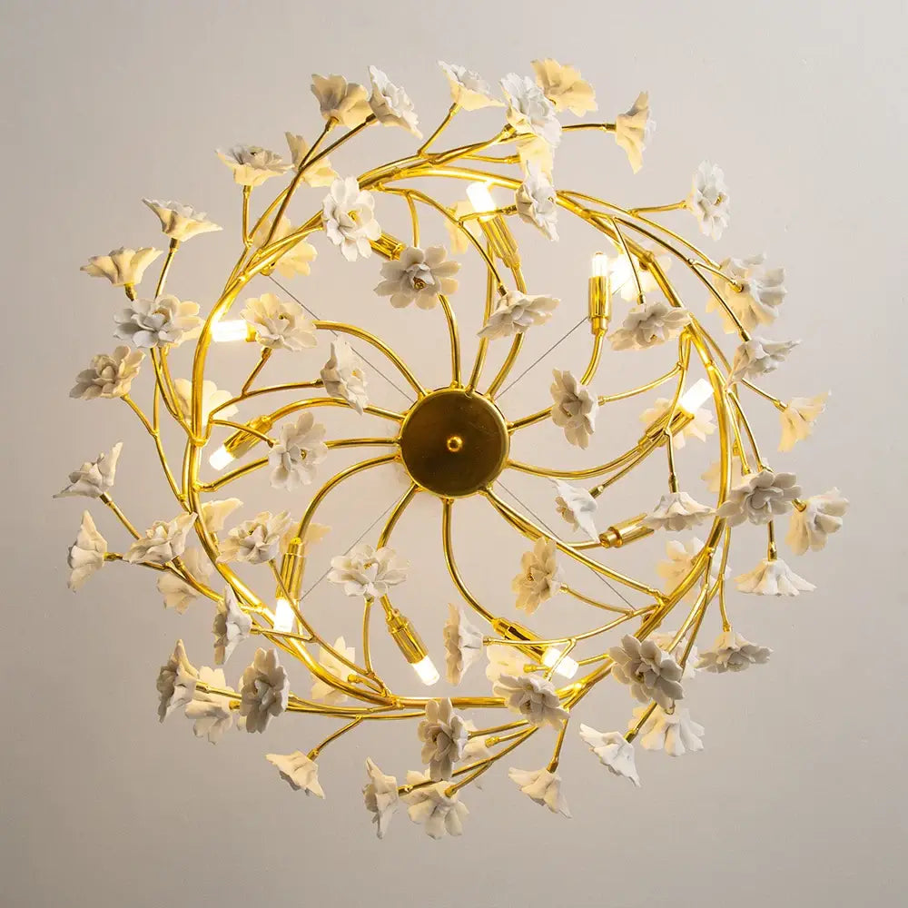 Golden chandelier with delicate french white flower ceramic branches from a central circular base for romantic home décor