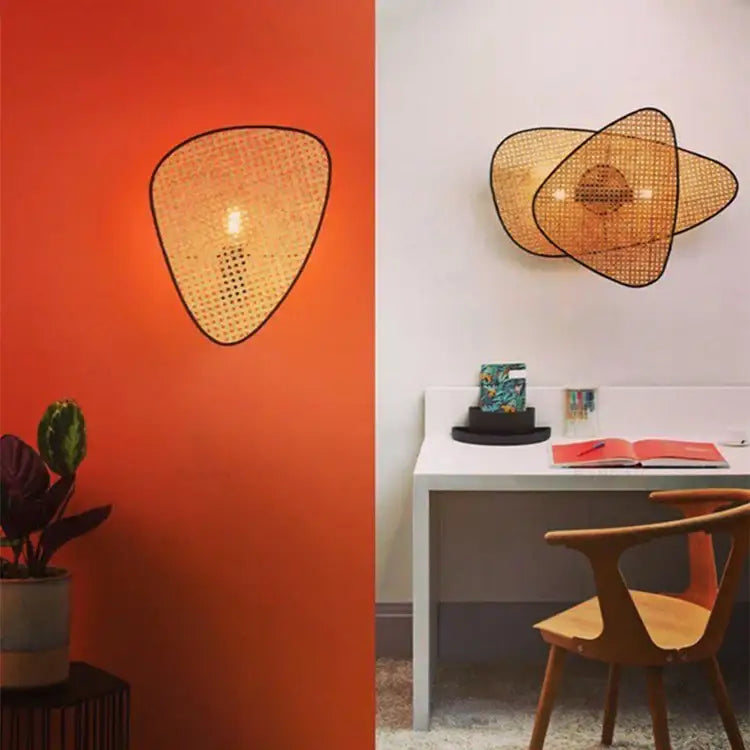 Woven rattan wall sconce with black frame and warm amber glow from DecorBites french design rattan chandelier collection