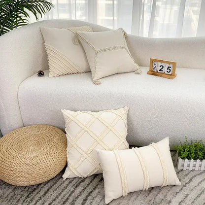 Cream-colored decorbites fringed geometry cushion covers with textured woven patterns and tassels on a cozy sofa