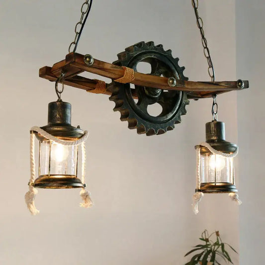 Decorbites gear industrial chandelier pendant featuring two glass lanterns with rope detail and metal gear on wooden beam