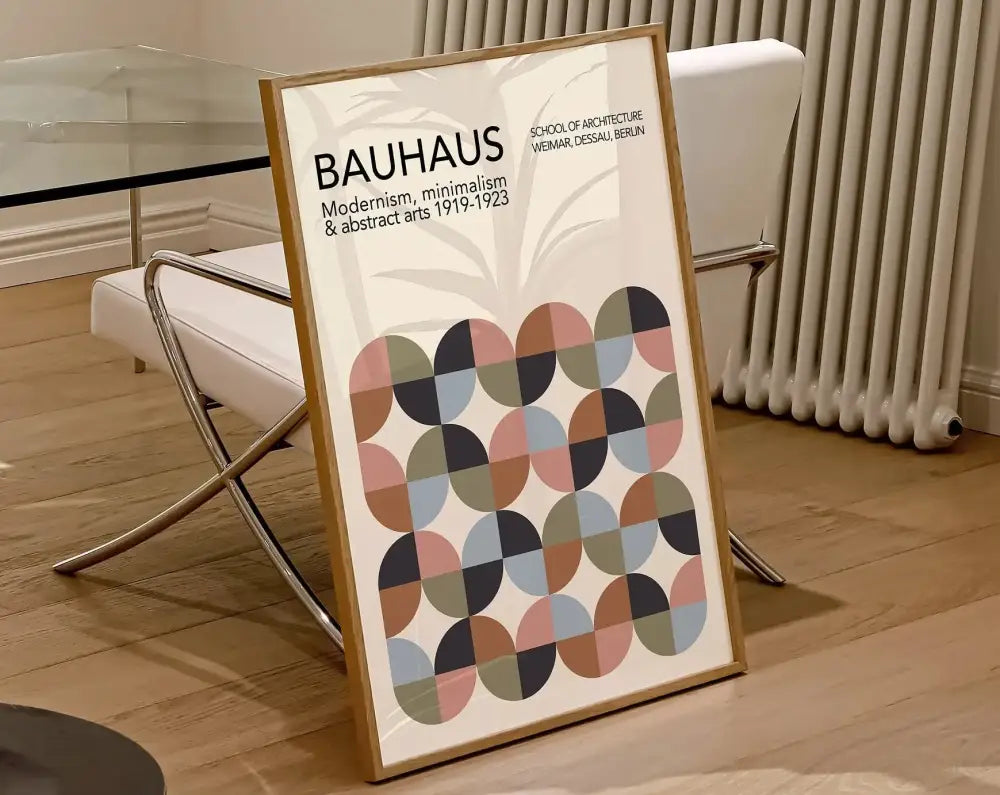 A framed canvas poster featuring a modernist bauhaus geometric pattern in muted pastels and earthy tones in a light wood frame