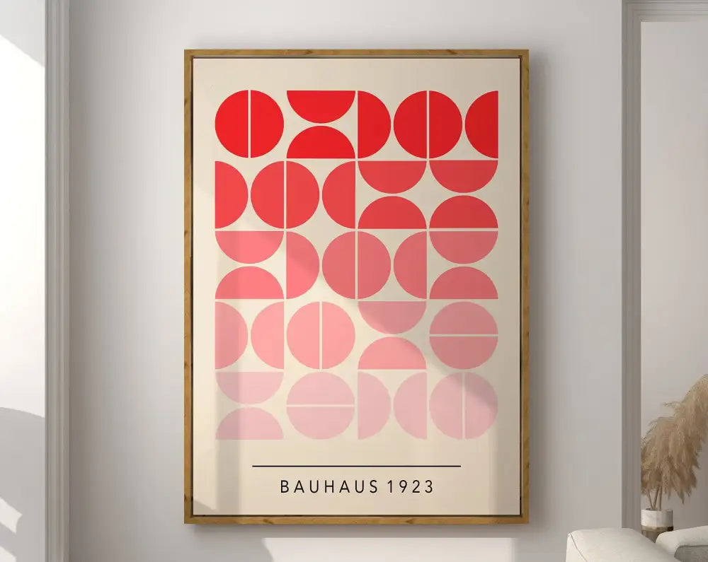 A framed decorbites™ geometric bauhaus canvas poster with red and pink semi circles in a light wood frame