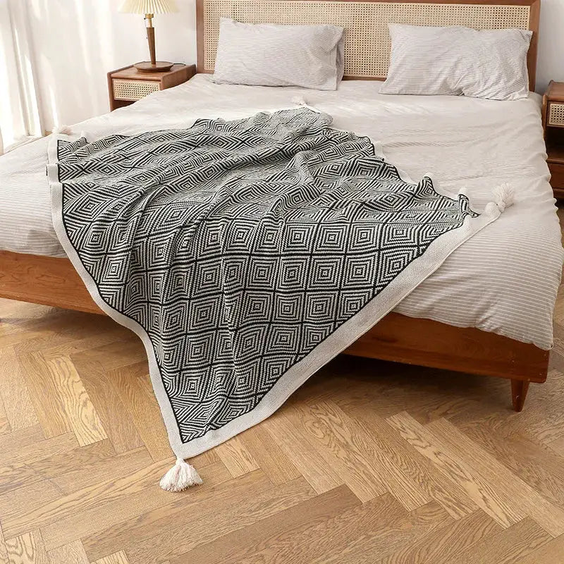 A cozy decorbites geometric tassel blanket in black and cream with textured weave and fluffy tassels for living room use