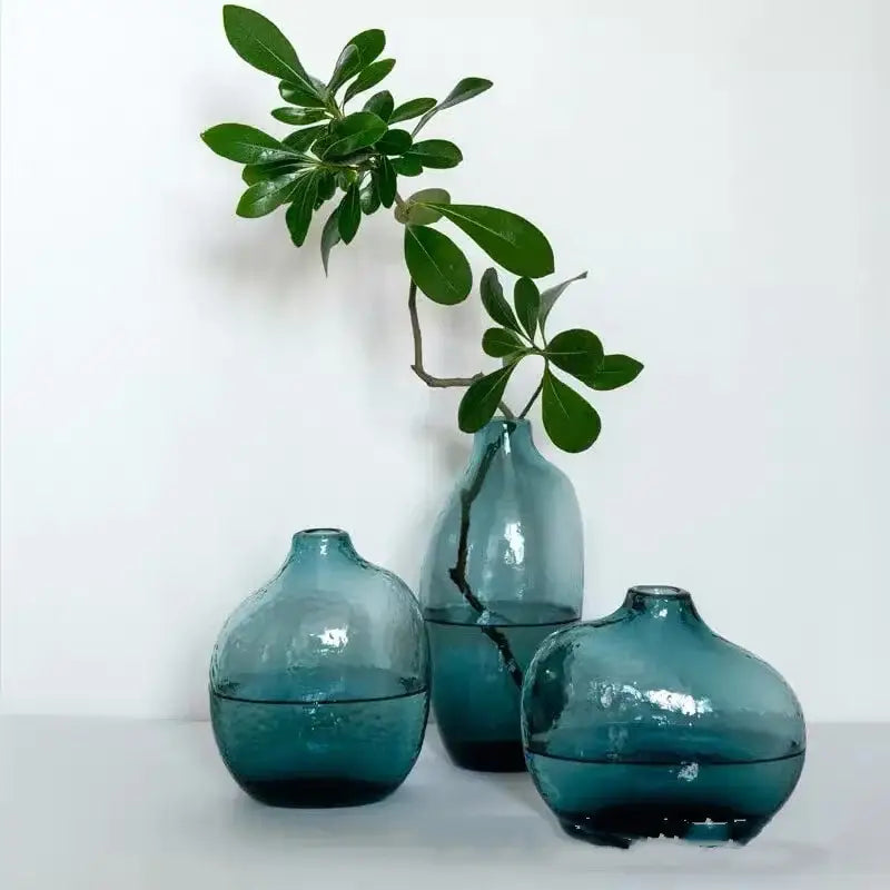 Three teal-blue glass vases with rounded bulbous shapes and textured finish for single flower geometric zen glass display