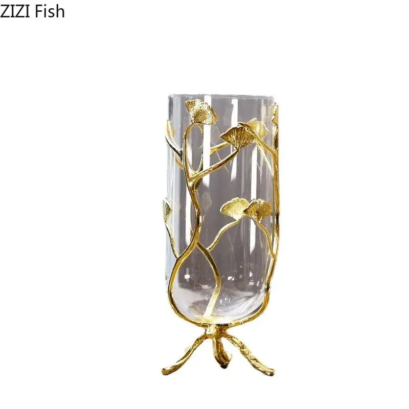 Clear glass vase with gold-toned ginkgo leaf metal accents on a matching three-legged base for modern decor