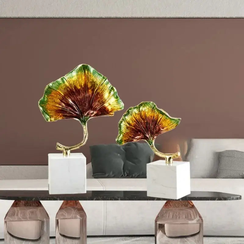 DecorBites ginkgo leaf metal sculpture featuring two glossy iridescent leaves with gold stems and white marble bases