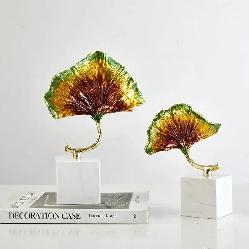 Decorbites ginkgo leaf metal sculpture featuring vibrant iridescent gold and green leaves on white marble bases