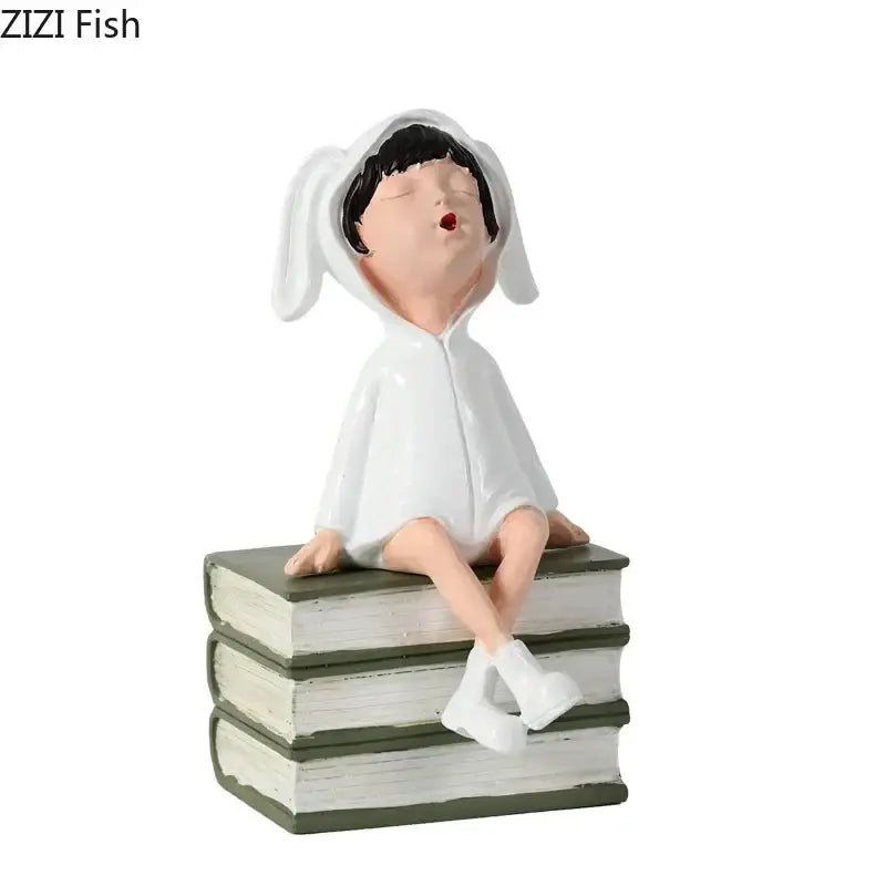 White bunny-eared resin sculpture figure sitting atop stacked books in DecorBites™ modern girls and books decor