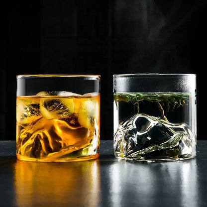Two clear glass decorbites glacier wine cups with amber whiskey and green tea showcasing Japanese style and Fuji artwork