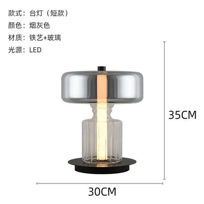A decorbites glass art desk lamp with a faceted glass base and smoked gray metallic top illuminated by led light