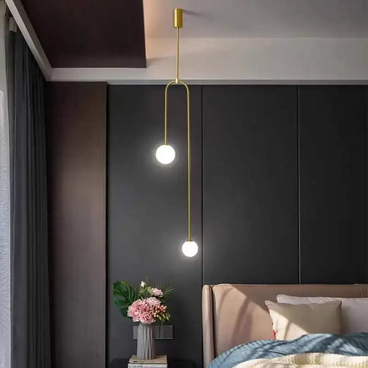 Gold-toned decorbites glass ball brass pendant lights with two spherical bulbs on a curved metal arm for bedroom lighting