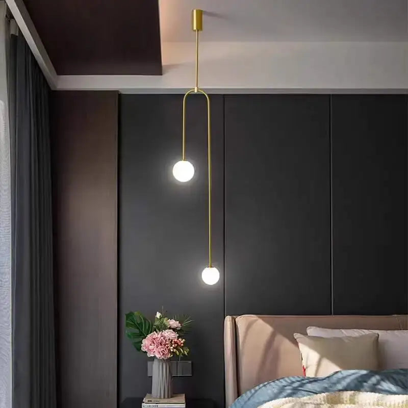Gold-toned decorbites glass ball brass pendant lights with two spherical bulbs on a curved metal arm for bedroom lighting