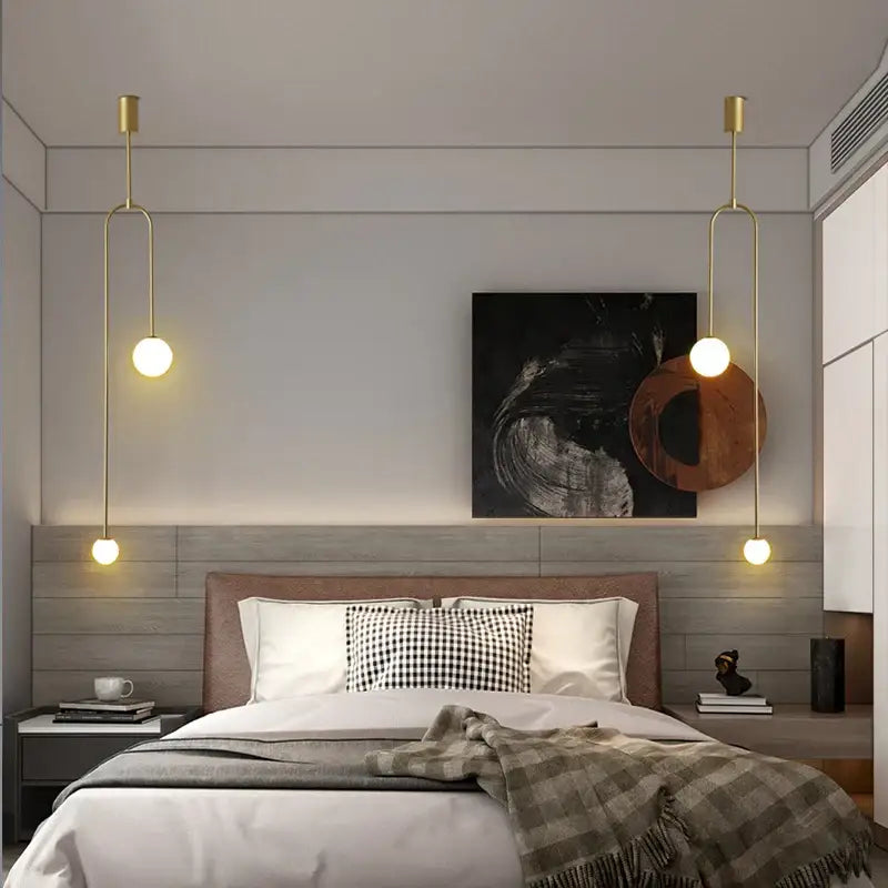 Gold-toned decorbites glass ball brass pendant lights with spherical bulbs hang symmetrically above the bed