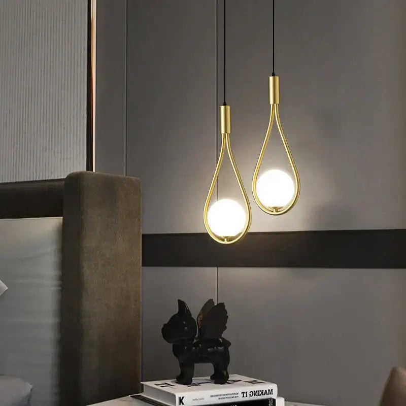 Two elegant gold-toned decorbites glass ball brass wall lamps with teardrop frames and glowing bulbs for bedroom lighting