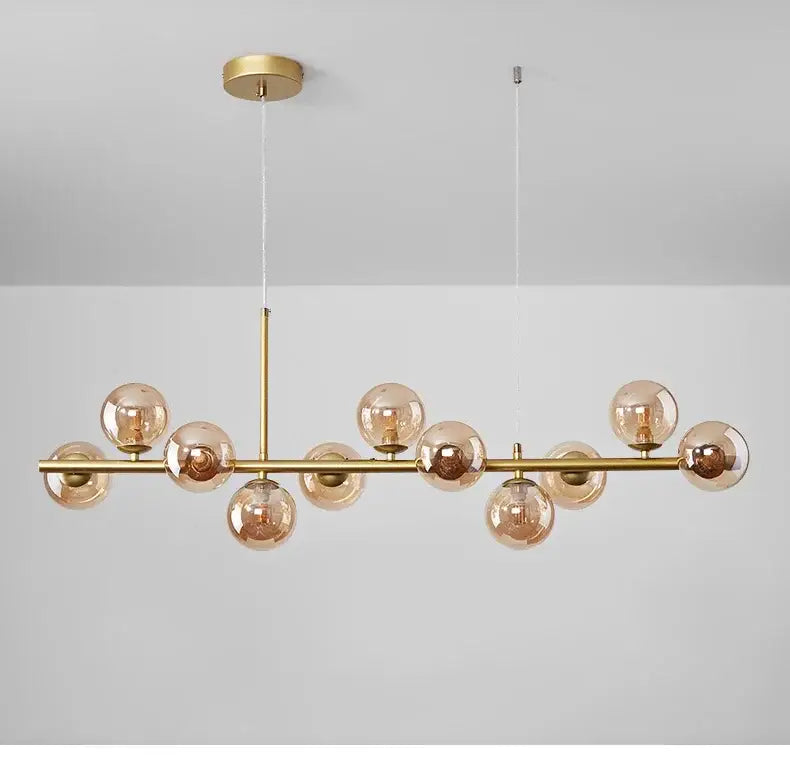 Gold-toned decorbites™ glass ball chandelier with amber glass globe bulbs on a sleek bar for dining room lighting