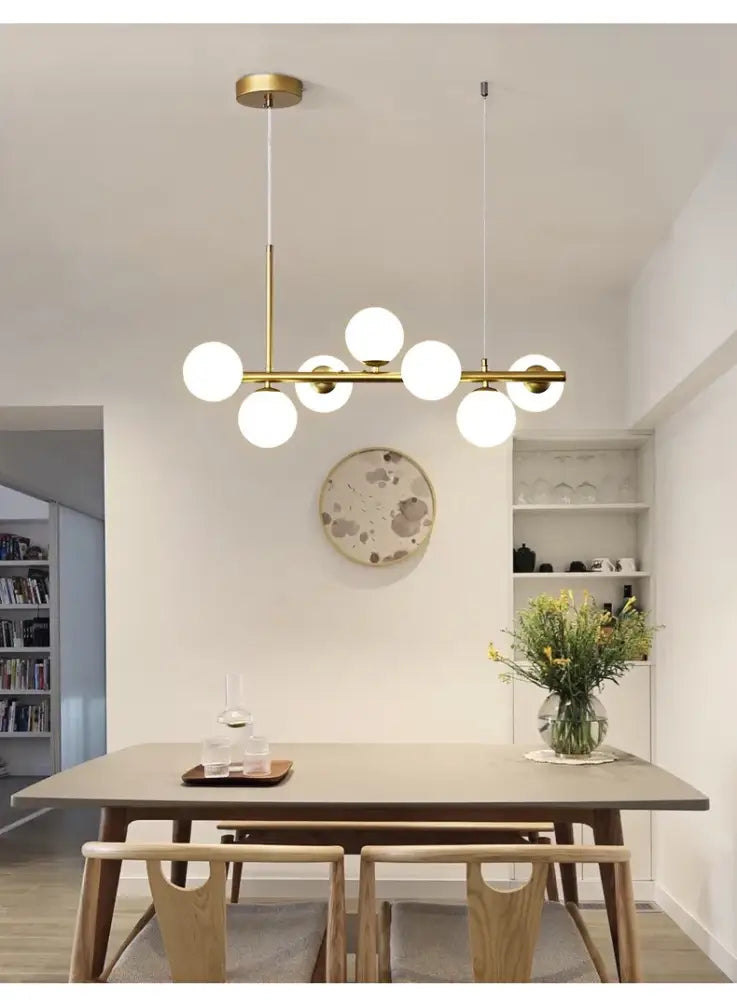 DecorBites™ gold-toned glass ball chandelier with multiple spherical bulbs in a modern linear design for home lighting