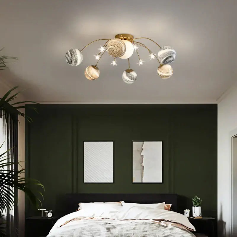 Gold-toned decorbites glass ball chandelier with planet-themed globes and star accents for kids and living rooms