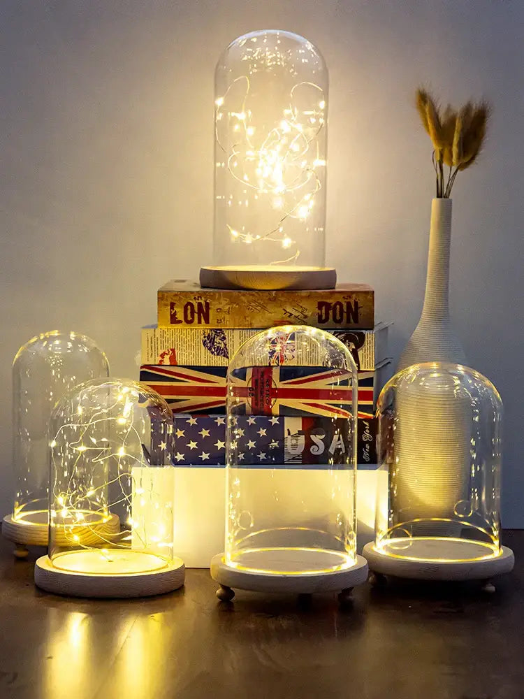 DecorBites glass bell jar terrarium with warm white LED string lights inside on a circular wooden base