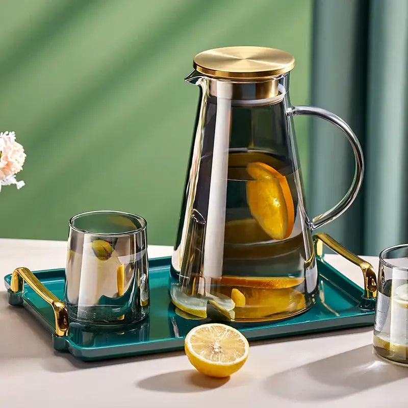 Clear glass tea jug with gold-toned lid and handle filled with lemon water from decorbites water kettle set
