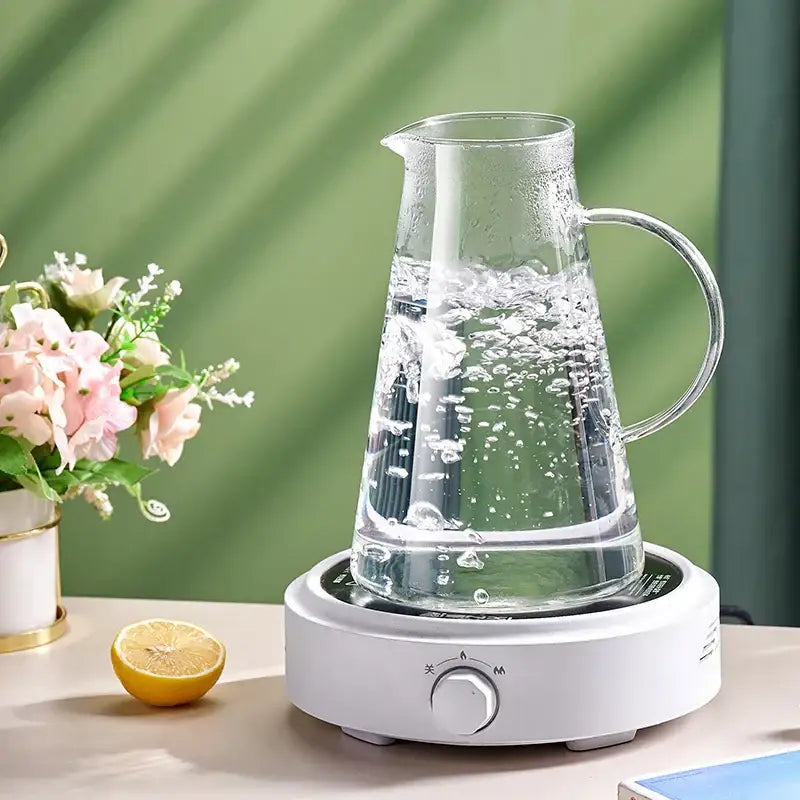 Clear glass tea jug with curved handle on white electric heating base from decorbites water kettle set