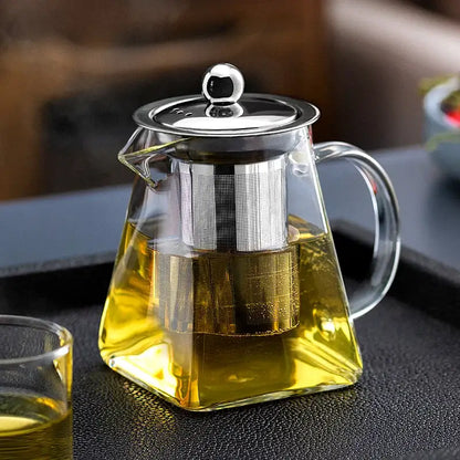 Clear glass tea pot with stainless steel infuser and lid filled with golden tea by DecorBites glass tea pot