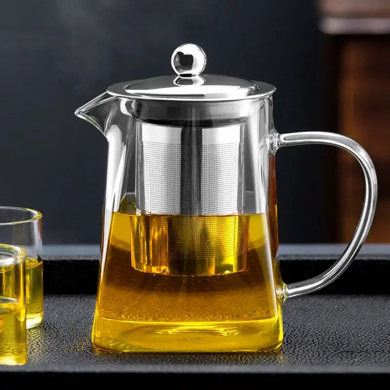 Clear glass tea pot with stainless steel lid handle and built-in filter holding golden tea from decorbites glass tea set