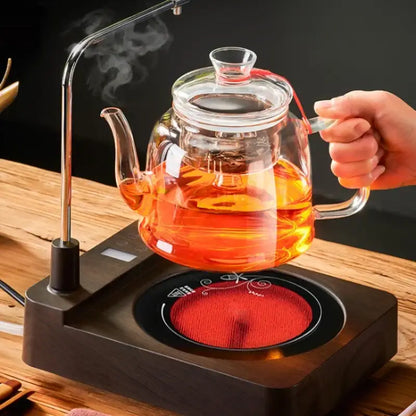 DecorBites™ glass tea pot set with red silicone lid and handle filled with steaming amber tea for brewing