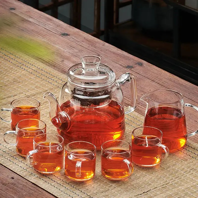Clear glass tea pot set with lid and handle filled with amber tea by DecorBites high quality filterable kettle
